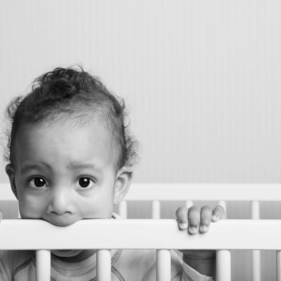 boy chewing edge of his baby crib