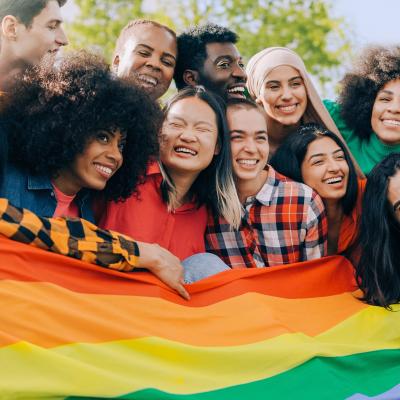 diverse people holding rainbow flag