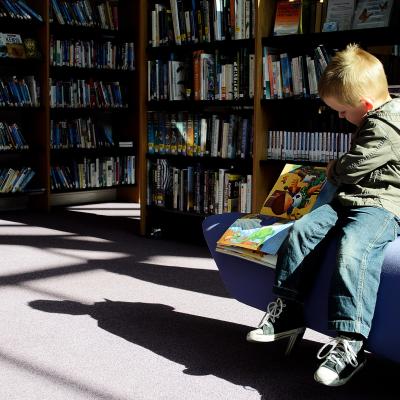 Child reading a book in a large library