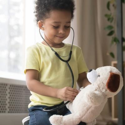 Child playing imaginary doctor with teddy bear