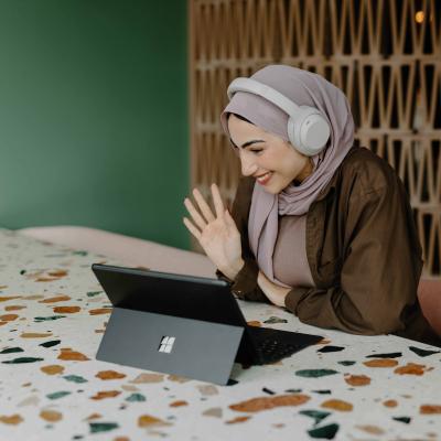 Women with hand raised looking at laptop