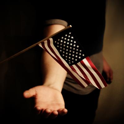 Dark image of a child holding a small United States flag