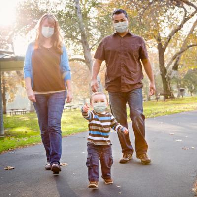 Family of three with masks walking outside