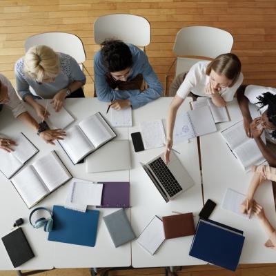 Arial view of students sitting around table with laptops and notebooks