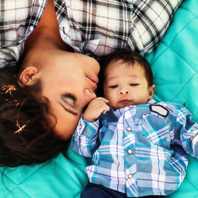 Teenage mom lying on a blanket with her infant child