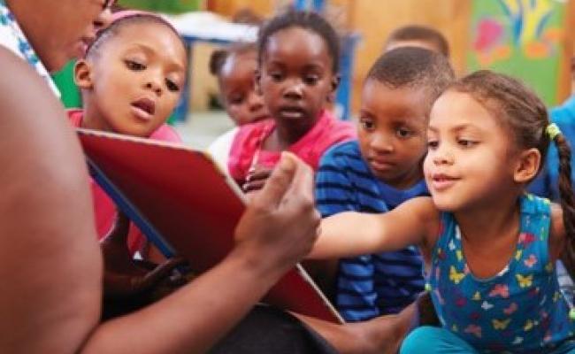 Teacher reading to and engaging class of young students 