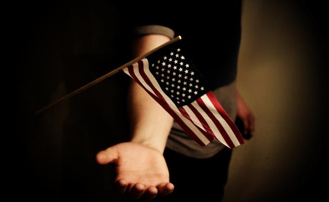 Dark image of a child holding a small United States flag
