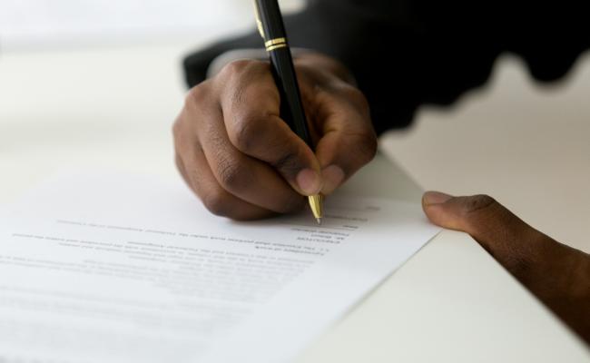 Image of hand signing a letter