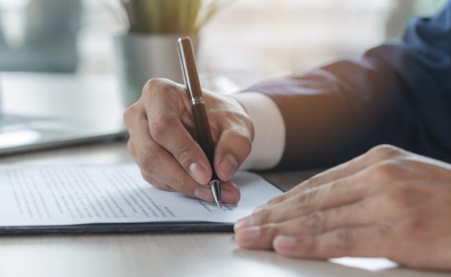 Image of hands, signing a letter