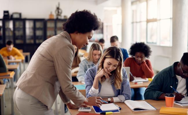 Teacher looking over student doing work in the classroom
