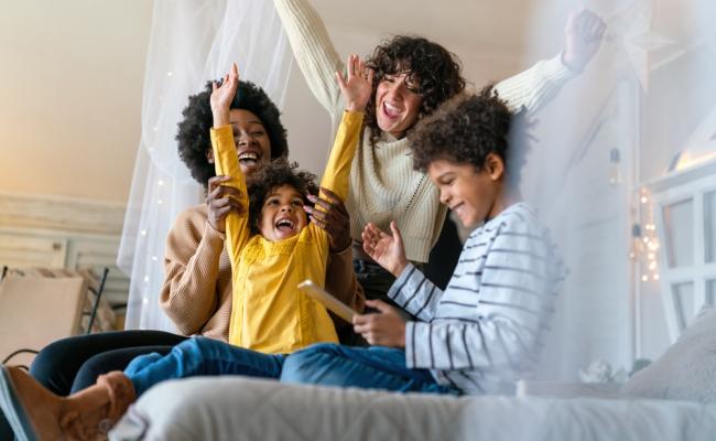 Image of family with hands up and sitting on a bed