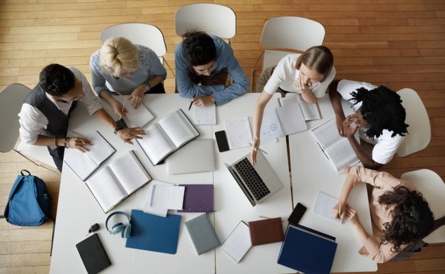 Arial view of students sitting around table with laptops and notebooks