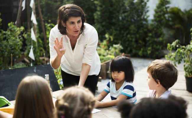 Female teacher talking to a group of young children